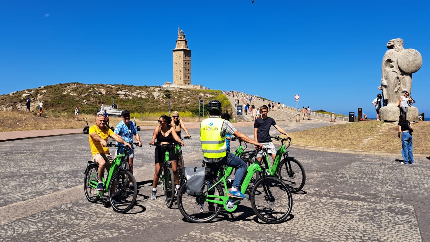 Grupo de eco-lógica con bicicletas y guía junto a la Torre de Hércules
